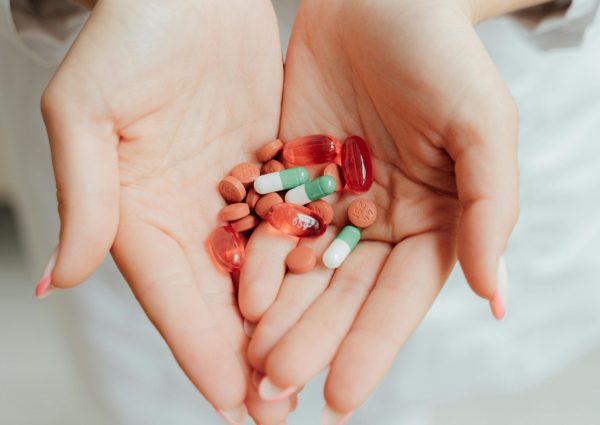Close-up of a person holding various pills and capsules in their hands, symbolizing healthcare and medicine.